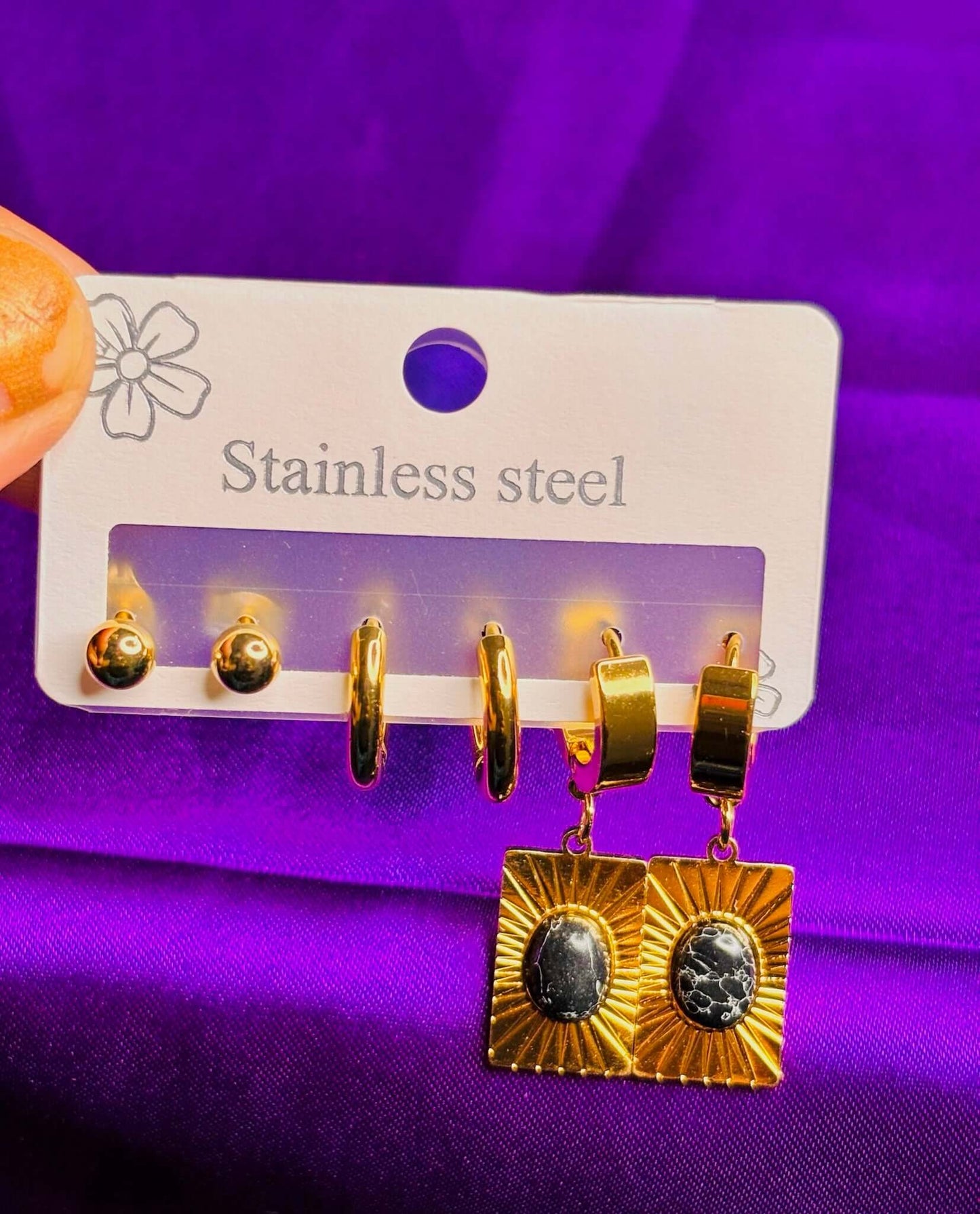 Bold black stone earring combo in stainless steel, featuring gold ball studs, hoops, and dramatic drop earrings.