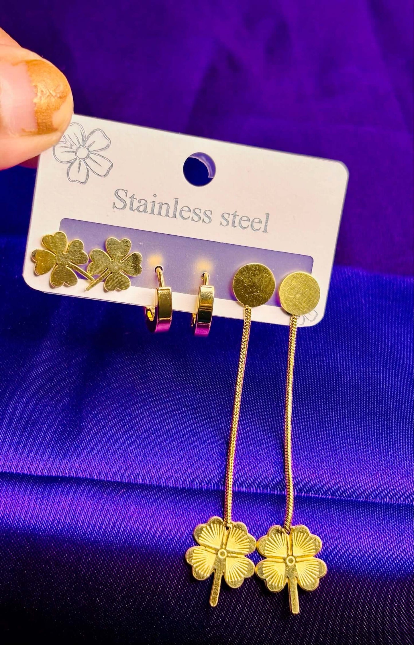 Clover-themed gold stainless steel earrings set of 3, including studs, hoops, and drop earrings, on a display card.