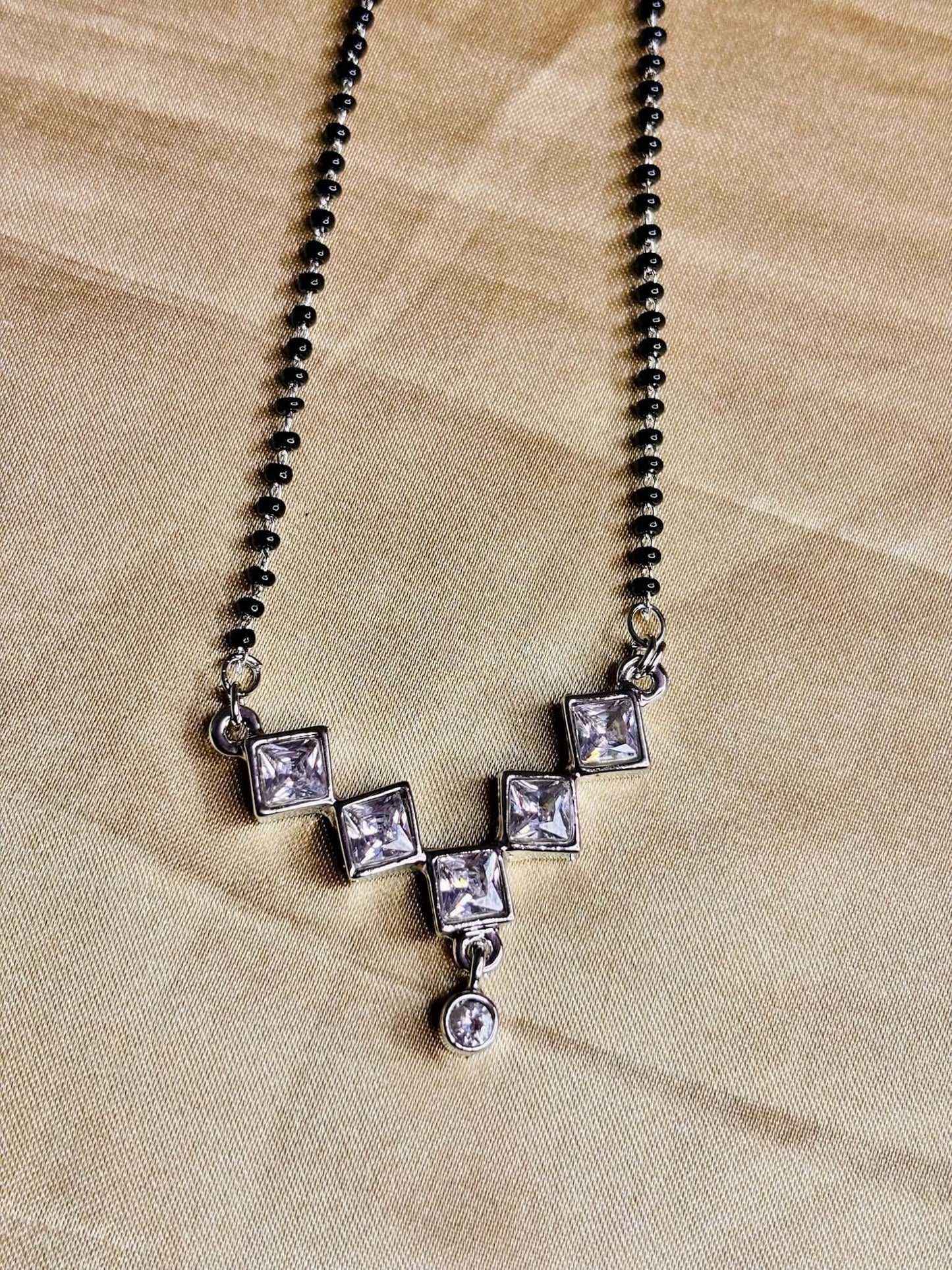 Modern silver diamond mangalsutra with square-cut American diamonds on a black beaded chain, ideal imitation jewelry.